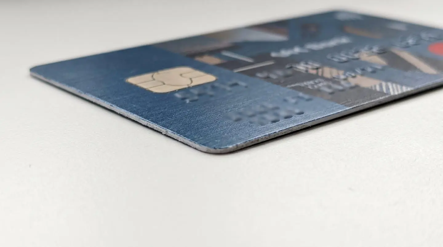 Détail en gros plan d'une carte bancaire montrant la texture de la puce électronique sur une surface blanche moderne